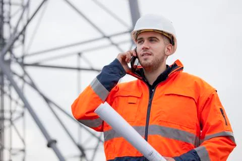 Young engineer or foreman talking  on smart phone on a oil platform or constr Фото