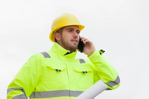 Young engineer or worker with green protective work wear talking on mobile ph 写真素材
