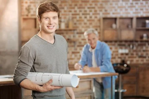 Young engineer posing with a finished blueprint 스톡 사진