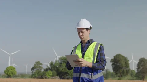 Young Engineer Safety Vest Using Tablet at Wind Farm Turbine Stock Footage 347053077