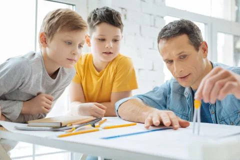 Young engineer showing sons how to measure distance with compass Stock Photos