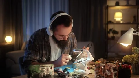 A young engineer is soldering an electronic board. A man is busy with his hobby Stock Footage 264051541