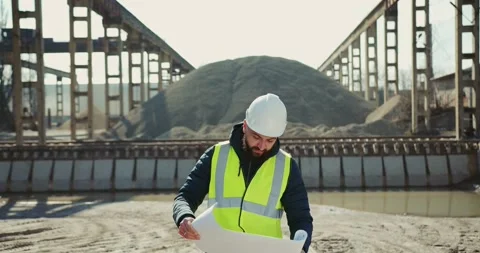 Young engineer standing with blueprint at construction site Stock Footage 277595863