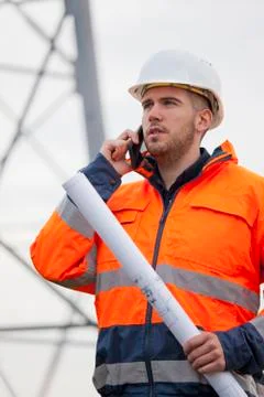Young engineer talking on smart phone in front of an oil rig or construction 写真素材