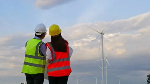 Young engineer team analyze a blueprint drawing of wind turbine farm. Stock Footage 157856505