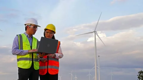 Young engineer team analyze with laptop computer against wind turbine farm. Video stock 157857105