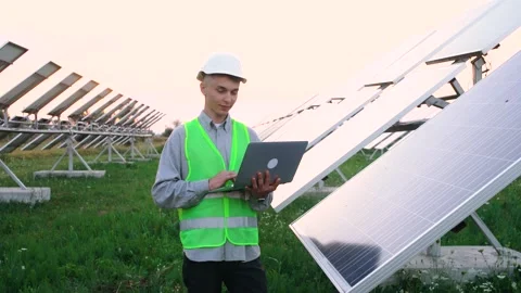 The young engineer uses his laptop near the solar panels. At the end he smiles Video stock 140206353