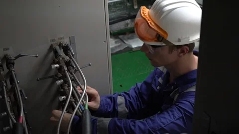 Young engineer in white helmet inspects hydraulic valves of cargo system Stock-Footage 118235115