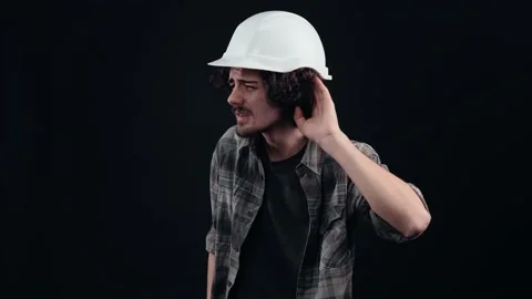 The young engineer, with a white helmet, puts his hand to his ear, he doesn't Stock Footage 156279754