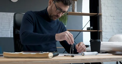 Young Engineer works in a Loft Office concentrates and draws blueprints with Stock Footage 126159860