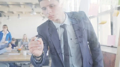 A young engineer writes formulas and graphs on a glass board using a marker Stock Footage 109565637