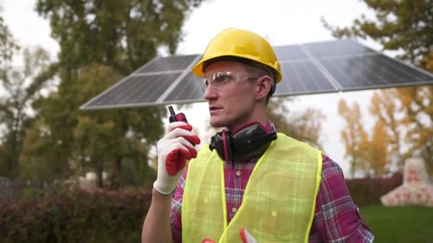 Young engineer in yellow helmet, protective clothing, glasses and gloves uses Stock Footage 292937737