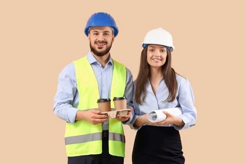 Young engineers with coffee cups on beige background Stock Photos