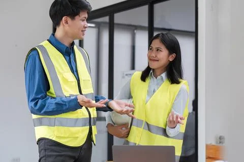 Young Engineers Collaborating on Construction Project Plans in Modern Office Foto stock