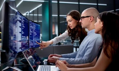 Young Engineers Leading Collaborative Coding Session In Busy Office Team 스톡 사진