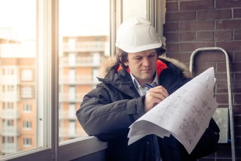 Young engineers using pen point to the blueprint paper to examine the structure Stock Photos