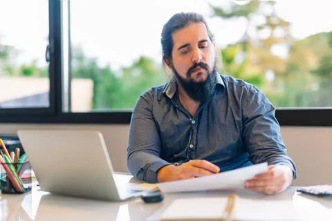 Young entrepreneur consulting documents while working at home Stock Photos