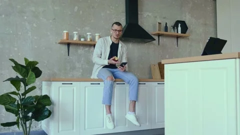 Young entrepreneur is eating an apple while having a video meeting in the Stock Footage 155753780