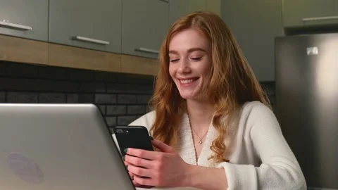 Young entrepreneur is smiling in the kitchen while using a laptop and chatting Video stock 150536881