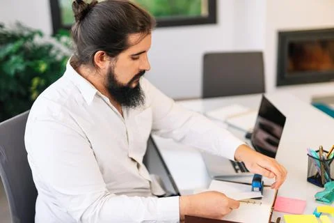 Young entrepreneur stapling papers while working at home. Stock Photos