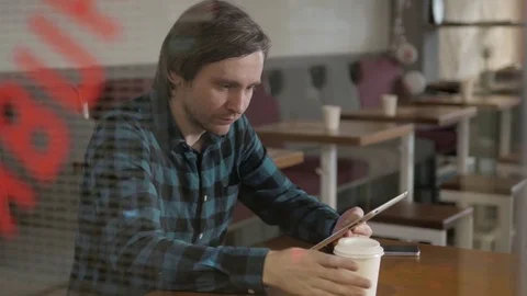 Young entrepreneur working in a cafe, window view freelancer in restaurant with Stock-Footage 76844416