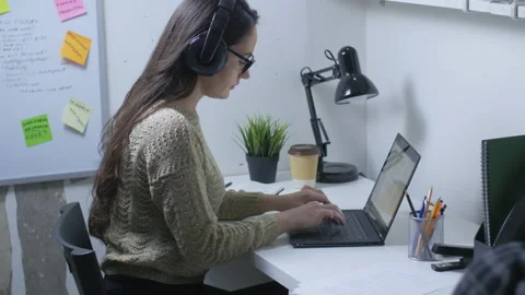 Young entrepreneur working with laptop while listening to music late at night Stock Footage 142329010