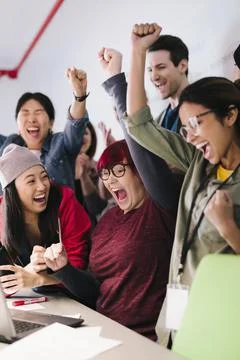 Young, excited computer programmers cheering in meeting Stock-Fotos
