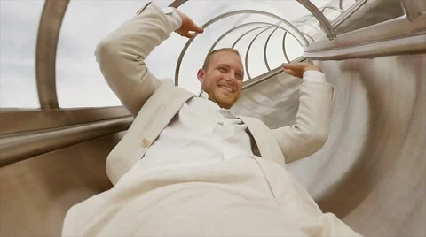 Young excited man having fun sliding down on slide in slow motion Stock Footage 42944335