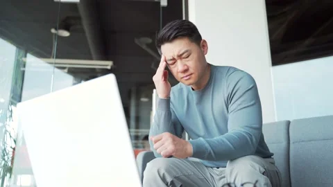 Young exhausted, overworked office worker sitting in the workplace with a severe Stock Footage 166233908