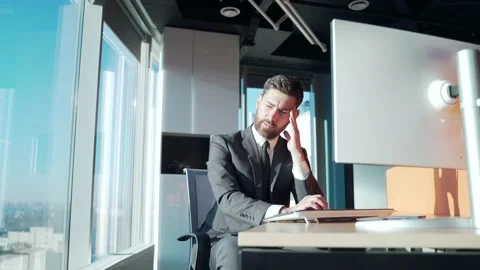 Young exhausted, overworked office worker sitting in the workplace with a severe Stock Footage 167861785