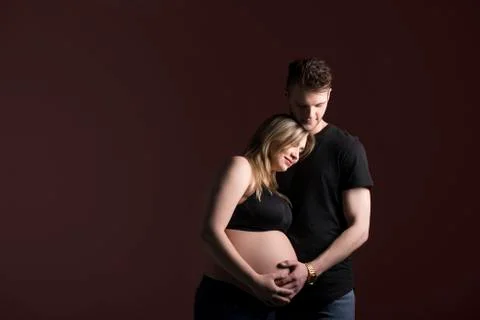 A young expectant couple looking down at their baby while they are holding her b Stock Photos