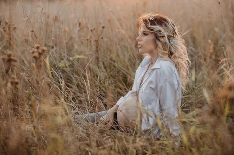 A young expectant mother in the third trimester of pregnancy is sitting in a  Stock Photos