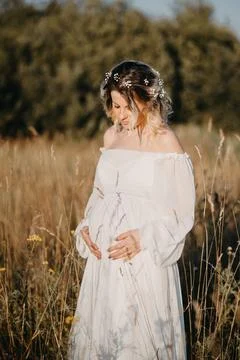 A young expectant mother in the third trimester of pregnancy in a white dress Stock Photos