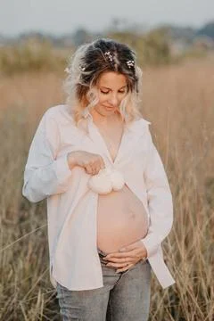 A young expectant mother in the third trimester of pregnancy in a white dress Stock Photos