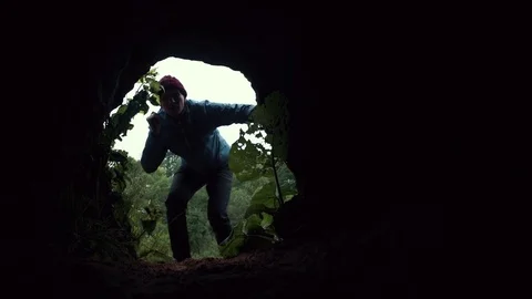 Young explorer looks into dark cave chamber with flashlight in his hand Stock Footage 80053794