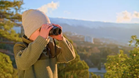 Young explorer using binoculars for bird watching in mountains Stock Footage 329769901