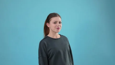 Young Expressive Woman Pointing Side Finger Gesture on Blue Background Stock Footage 344777654