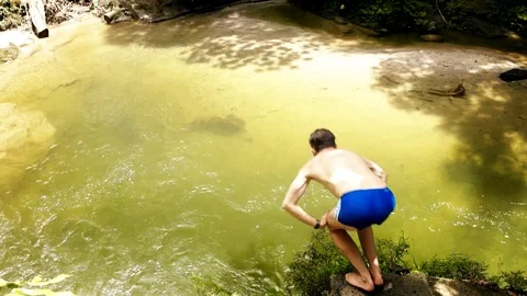 Young extreme guy diving into the natural pond with fresh green water in ecuador Stock Footage 97408635
