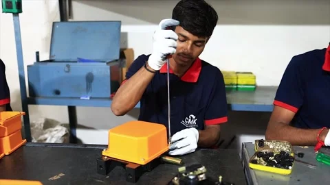 Young Factory Worker Assembling an Orange Industrial Component with a Stock Footage 318946493