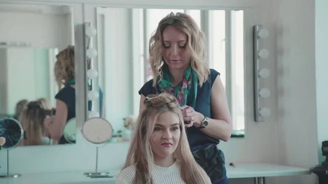 Young fair-haired woman in a white sweater came to the beauty salon Stock Footage