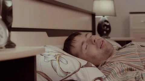 Young fair-skinned man sleeping in his bed has a nightmare which makes him turn Видео 68421396