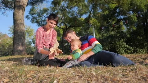 Young family with Baby Boy Enjoying Sunny evening in the Park. Slow Motion Stock Footage