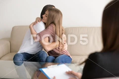 Young family couple hugging sitting on couch, consulting female Stock Photos