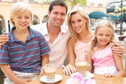 Young Family Enjoying Cup Of Coffee In Café Together Stock Photos