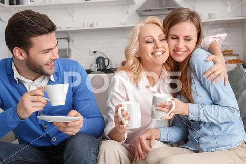 Young family with mother-in-law at home weekend drinking coffee Stock Photos