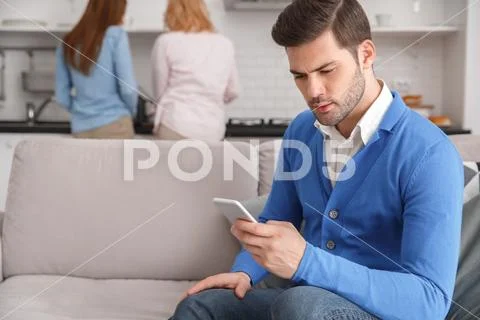 Young family with mother-in-law at home weekend guy browsing smartphone Stock Photos