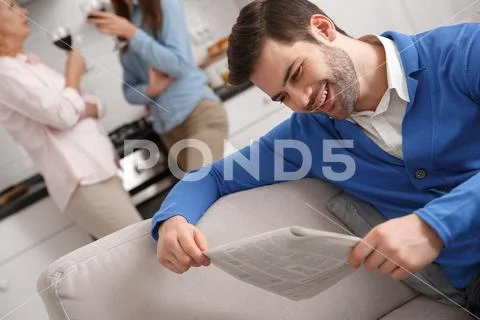Young family with mother-in-law at home weekend guy reading newspaper Stock Photos