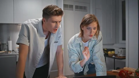 Young family preparing dinner in evening together. Relaxed couple watch laptop Stock Footage 333269233