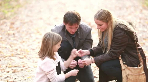 Young family sitting on pathway and playing games Stock Footage 59554359