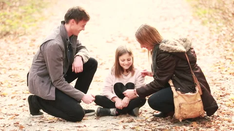Young family sitting on pathway and playing games Stock Footage 59554372